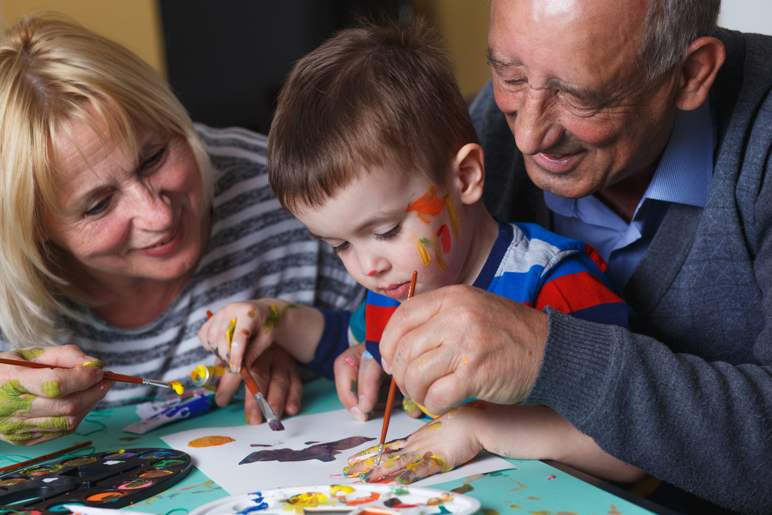 Grandmother and grandfather with grandson drawing together at ho